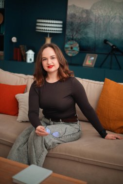 Gündüz vakti rahat bir duruşla koltukta oturan psikolog.