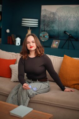 Gündüz vakti rahat bir duruşla koltukta oturan psikolog.