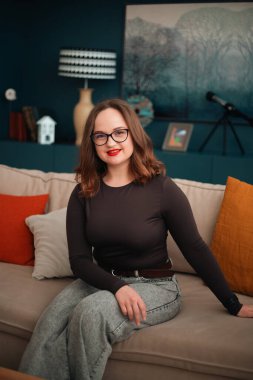 Gündüz vakti rahat bir duruşla koltukta oturan psikolog.