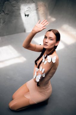 Model, gündüz saatlerinde stüdyoda el kaldırırken teninde kelebekler ile poz verir.