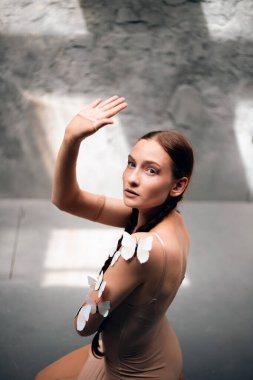 Model, gündüz saatlerinde stüdyoda el kaldırırken teninde kelebekler ile poz verir.