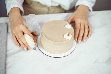 Şekerci bütün gün mutfak tezgahında kremalı çiçeklerle pasta süslüyor.