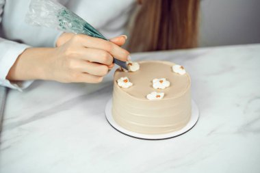 Şekerci bütün gün mutfak tezgahında kremalı çiçeklerle pasta süslüyor.