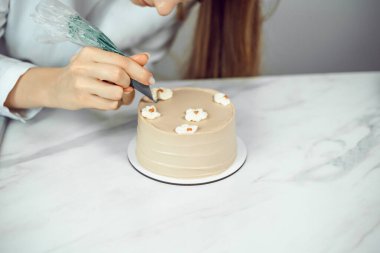 Şekerci bütün gün mutfak tezgahında kremalı çiçeklerle pasta süslüyor.