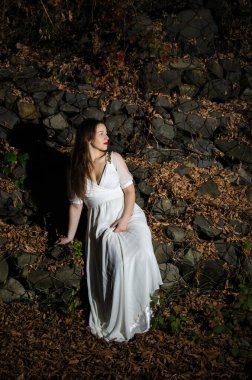 Güzel dikey portre. Şehvetli bir kadının görüntüsü, yüksek ve renkli bir beden, sokakta beyaz bir elbise içinde..