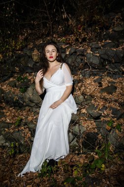 Güzel dikey portre. Şehvetli bir kadının görüntüsü, yüksek ve renkli bir beden, sokakta beyaz bir elbise içinde..