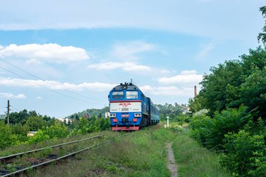 CHERNIVTSI, UKRAINE - 09 Ağustos 2021. DPL1-004 treni ve 2M62-1114 lokomotifi Chernivtsi sokaklarında yolcularla yolculuk ediyor..