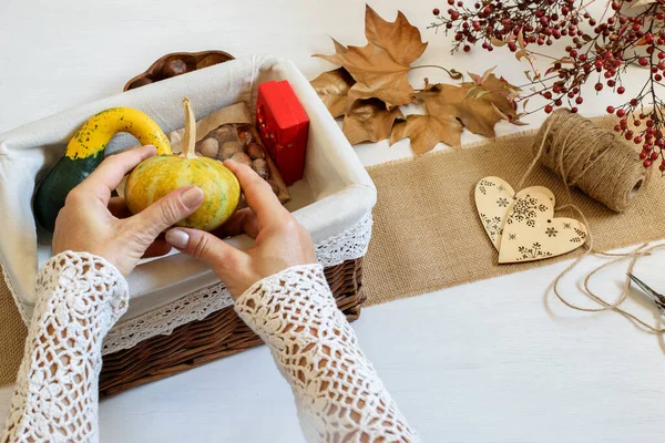 Female hands packing Halloween presents decorative pumpkins and nuts in craft gift box. Ethical shopping ideas, eco friendly and DIY concept.