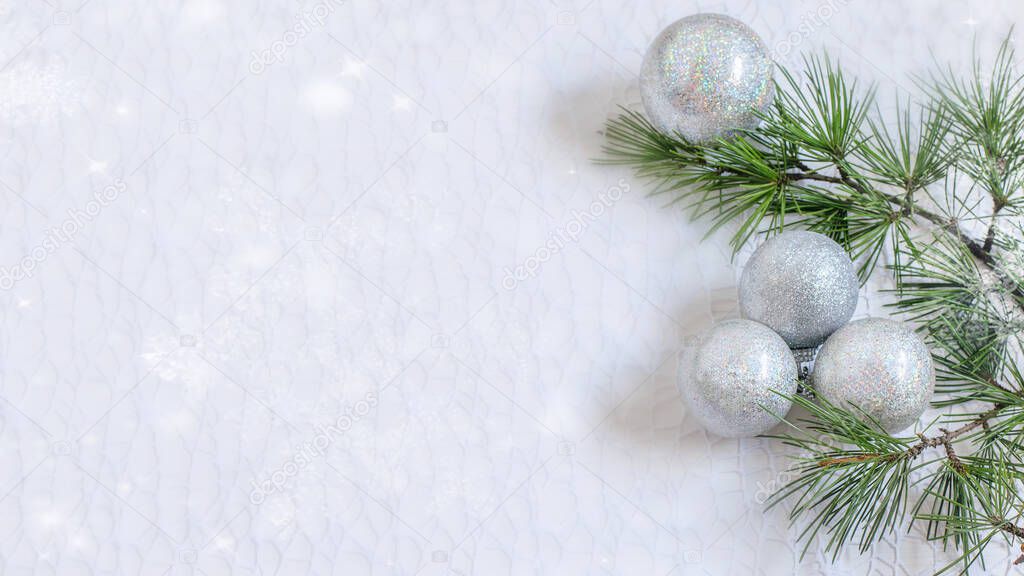 Christmas light sparkle background with christmas tree branch and shiny silver spheres. 