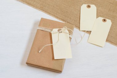 Boş kartlarla geri dönüşümlü el yapımı el yapımı kağıtlara sarılmış alternatif bir hediye. Desenli grunge çuval bezi arka planı. Sıfır atık, plastik hediye kutusu, sahte fotoğraf..
