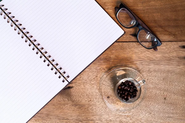 Kaffeetasse auf dem Tisch mit Tagebuch und Gläsern. — Stockfoto