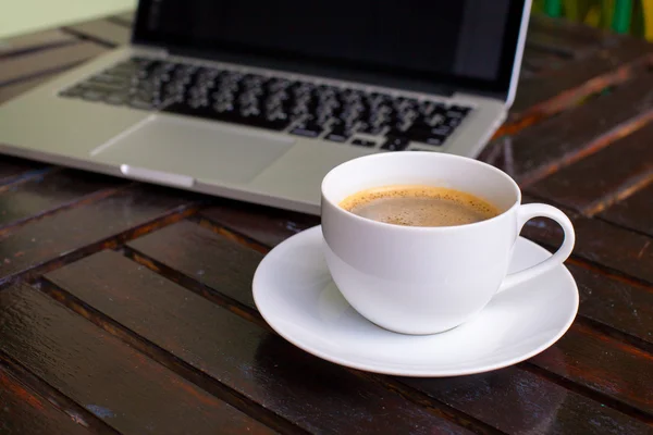 Taza de café con leche caliente en una taza blanca en un portátil de mesa en el café —  Fotos de Stock