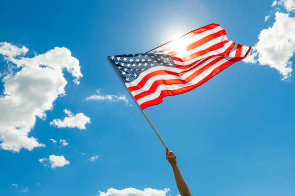 EUA bandeira na mão com lindas nuvens brancas e o céu azul sobre fundo — Fotografia de Stock