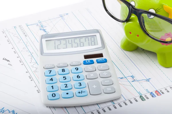 Grafici di mercato con la banca piggy di colore verde ed il calcolatore sopra esso — Foto Stock