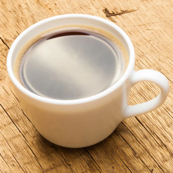 Cup of black coffee on old wooden table - close up studio shot — Stock Photo, Image