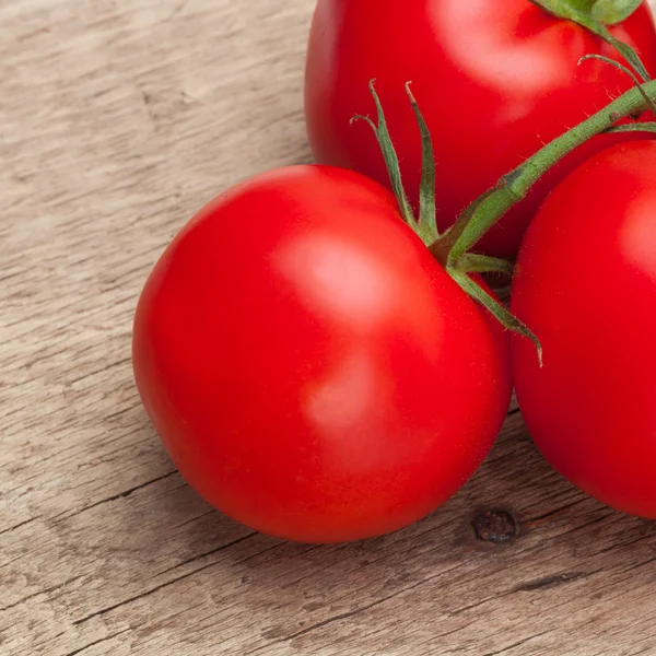 Several red tomatoes on rustic wooden table - close up shot — Stock Photo, Image