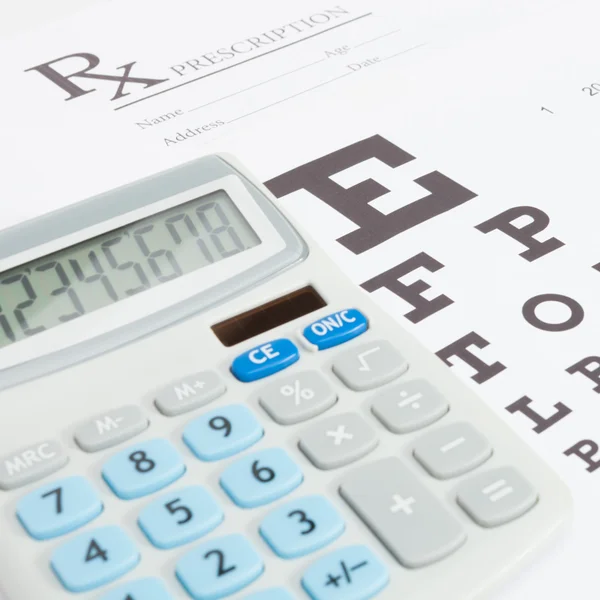 Table for eyesight test and medical prescription form with calculator ove it - close up studio shot — Stock Photo, Image
