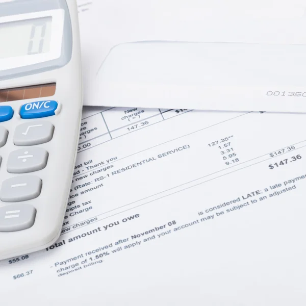 Close up studio shot of a calculator with utility bill under it — Stock Photo, Image