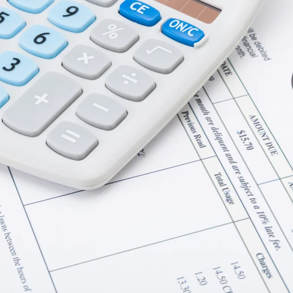 Close up shot of a calculator with monthly utility bill under it — Stock Photo, Image