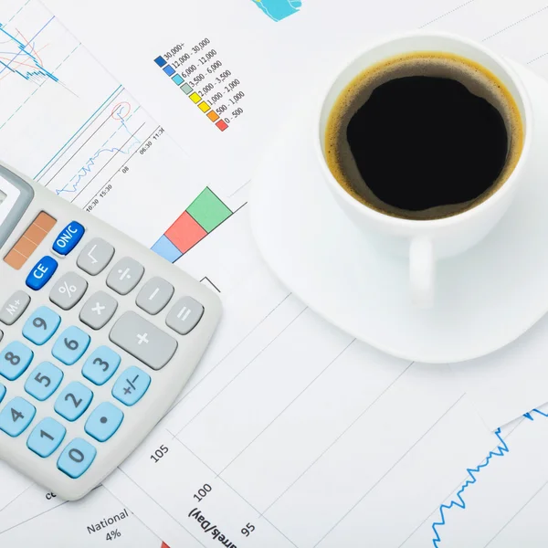 Close up shot of a coffee cup and calculator over world map and financial charts — Stock Photo, Image