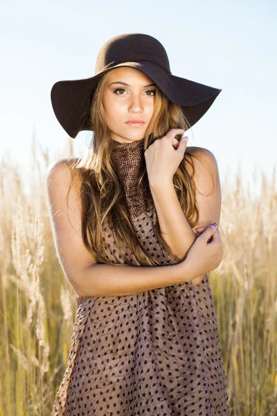 Beautiful young lady model posing in front of camera in a field at sunrise — Stock Photo, Image