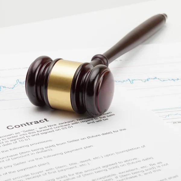 Close up studio shot of a wooden judge's gavel being put over contract — Foto Stock