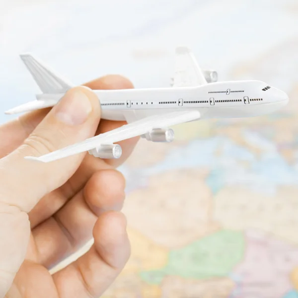 Traveling, tourism, communications and all things related - toy plane in hand and world map on background — Stock Photo, Image