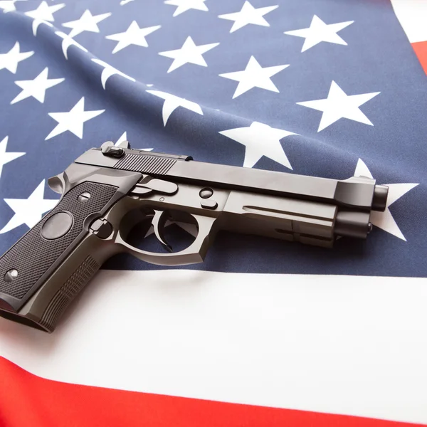 Close up studio shot of ruffled national flag with hand gun over it series - United States Photo De Stock