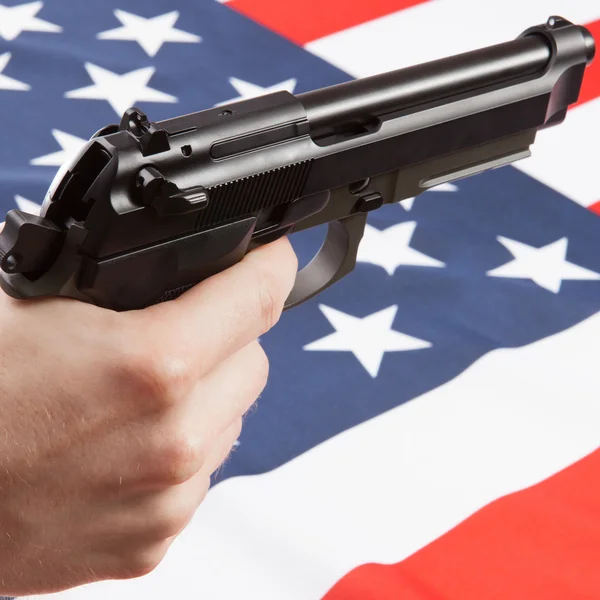 Hand gun over ruffled national flag - United States — Stock Photo, Image