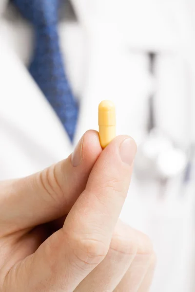 Medico maschio holdling una pillola con le sue dita - colpo dello studio — Foto Stock