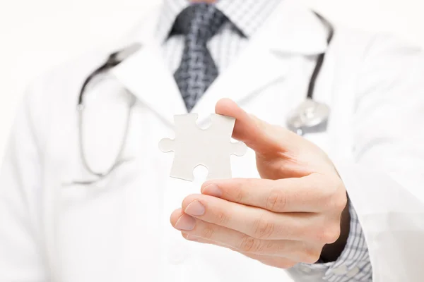 Doctor holding due pezzi di puzzle nelle sue mani - chiuda il colpo dello studio — Foto Stock