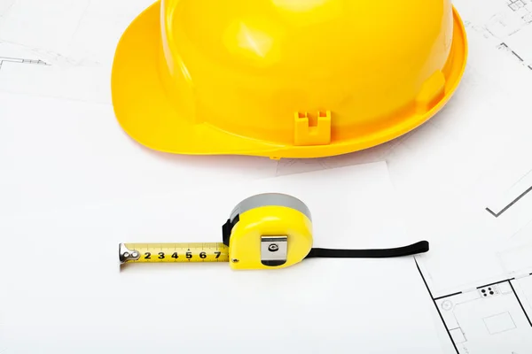 Casque de chantier jaune avec du ruban de mesure près d’elle — Photo