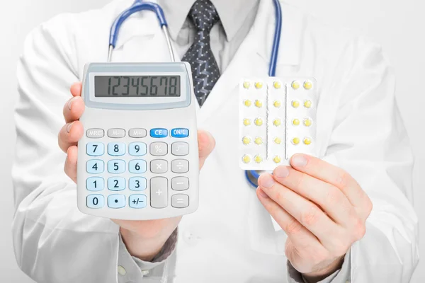 Doctor holdling calculadora y pastillas en sus manos - concepto de cuidado del brezo — Foto de Stock