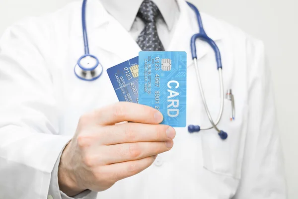 Doctor con dos tarjetas de crédito en su mano - closeup studio disparó —  Fotos de Stock