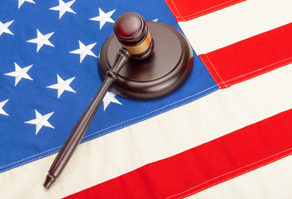 Wooden judge gavel and soundboard laying over US flag — Stock Photo, Image