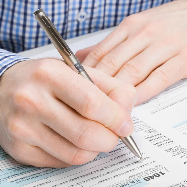 Male filling out 1040 United States of America Tax Form - studio shot - 1 to 1 ratio — Stock Photo, Image