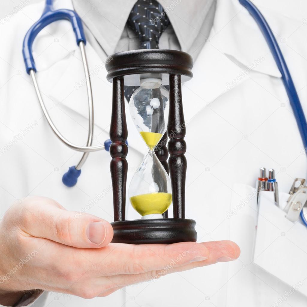 Doctor holdling in his hand a hourglass - heath care concept - 1 to 1 ratio