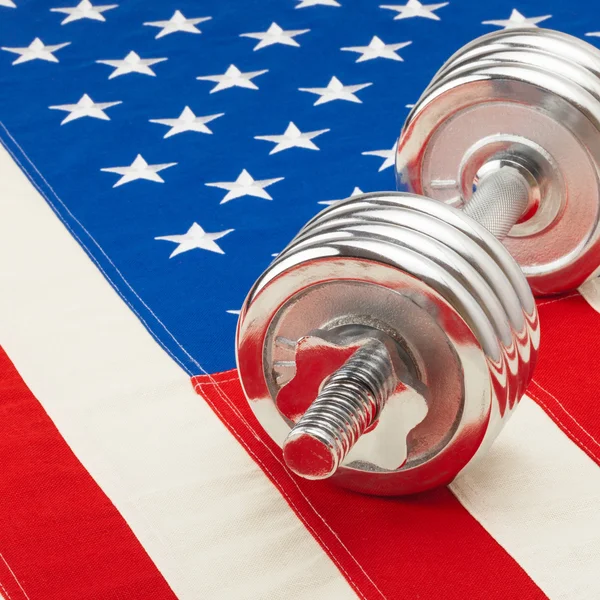 Metal dumbbell over US flag as symbol of healthy life style - 1 to 1 ratio — Stock Photo, Image