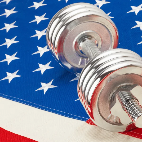 Metal dumbbell over US flag as symbol of healthy life style - 1 to 1 ratio — Stock Photo, Image