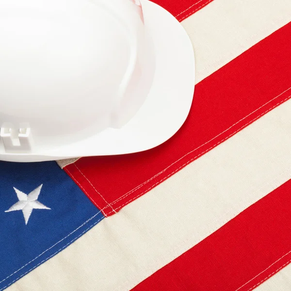 Casco de construcción de color blanco tendido sobre nosotros la bandera - 1 a 1 cociente — Foto de Stock