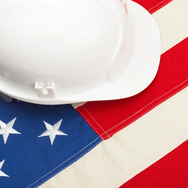 Casco de construcción de color blanco tendido sobre nosotros la bandera - 1 a 1 cociente —  Fotos de Stock