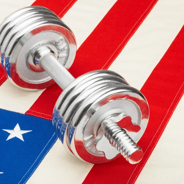 Metal dumbbells over US flag as symbol of healthy nation - 1 to 1 ratio — Stock Photo, Image