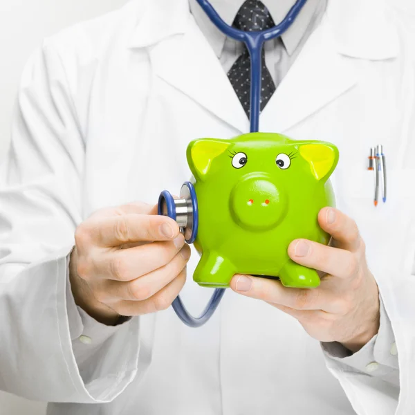 Médico sosteniendo en la mano - estetoscopio y piggybank relación 1 a 1 — Foto de Stock