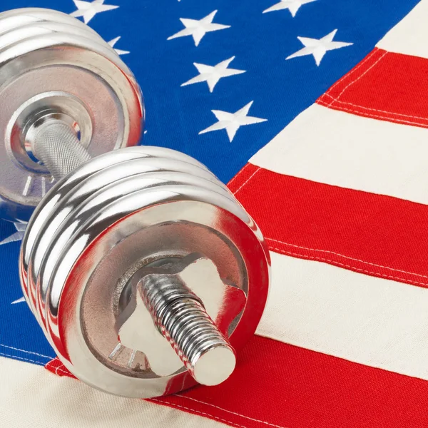 Metal dumbbell over big US flag - healthy life style concept - 1 to 1 ratio — Stock Photo, Image