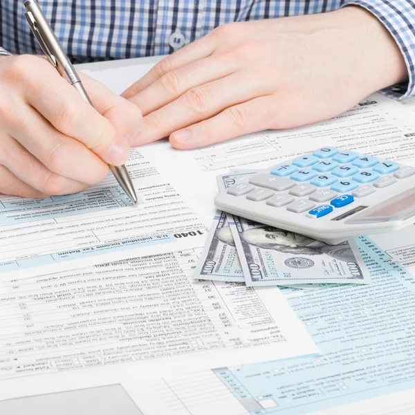 Man filling out 1040 US Tax Form - studio shot - 1 to 1 ratio — Stock Photo, Image