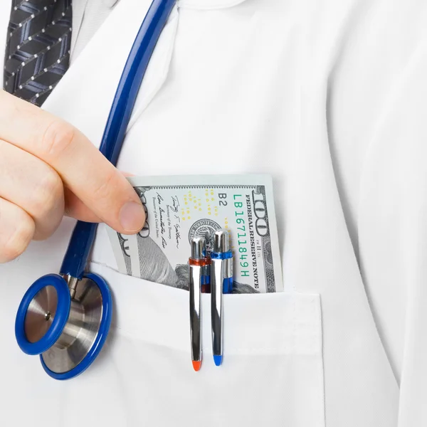 Doctor putting money into his pocket - studio shot — Stock Photo, Image