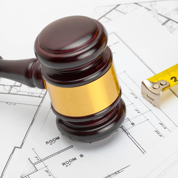 Judge gavel with measure tape above construction blueprin — Stock Photo, Image