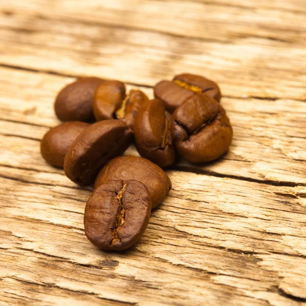 Neat roasted coffee beans on old wooden table — Stock Photo, Image