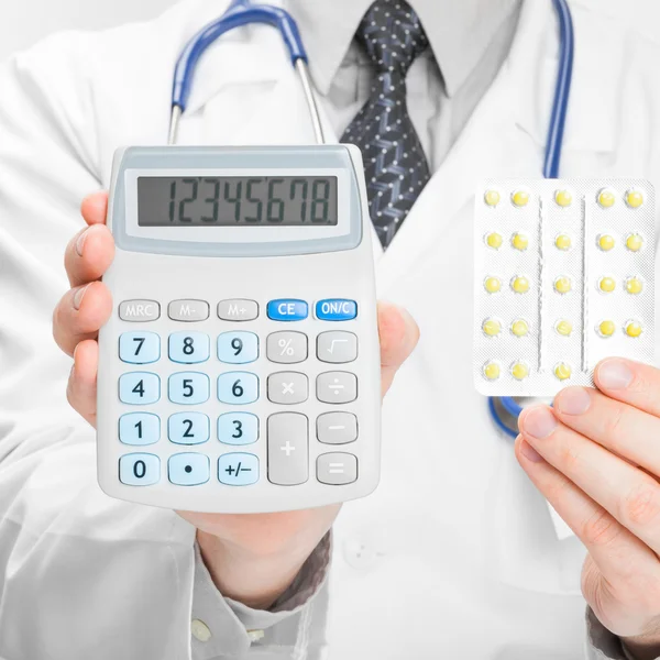 Doctor holdling calculator and pills in his hands - medical aid concept — Stock Photo, Image