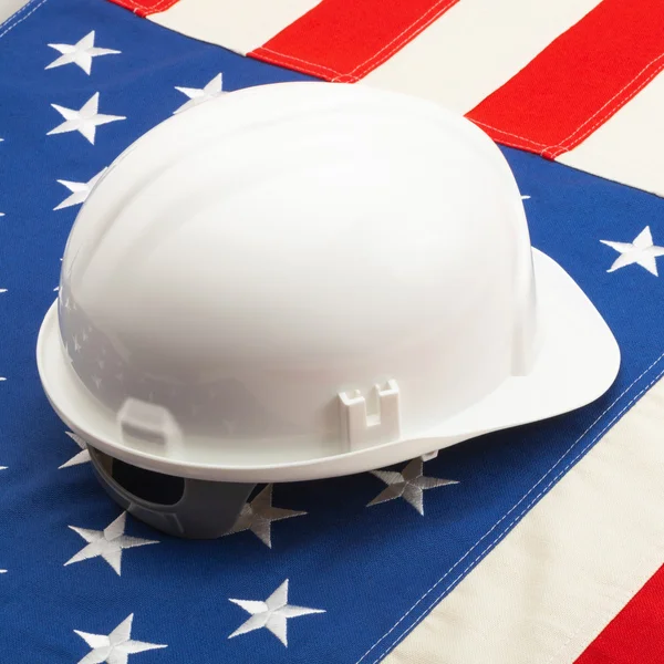 White color construction helmet laying over US flag - construction industry concept — Stock Photo, Image